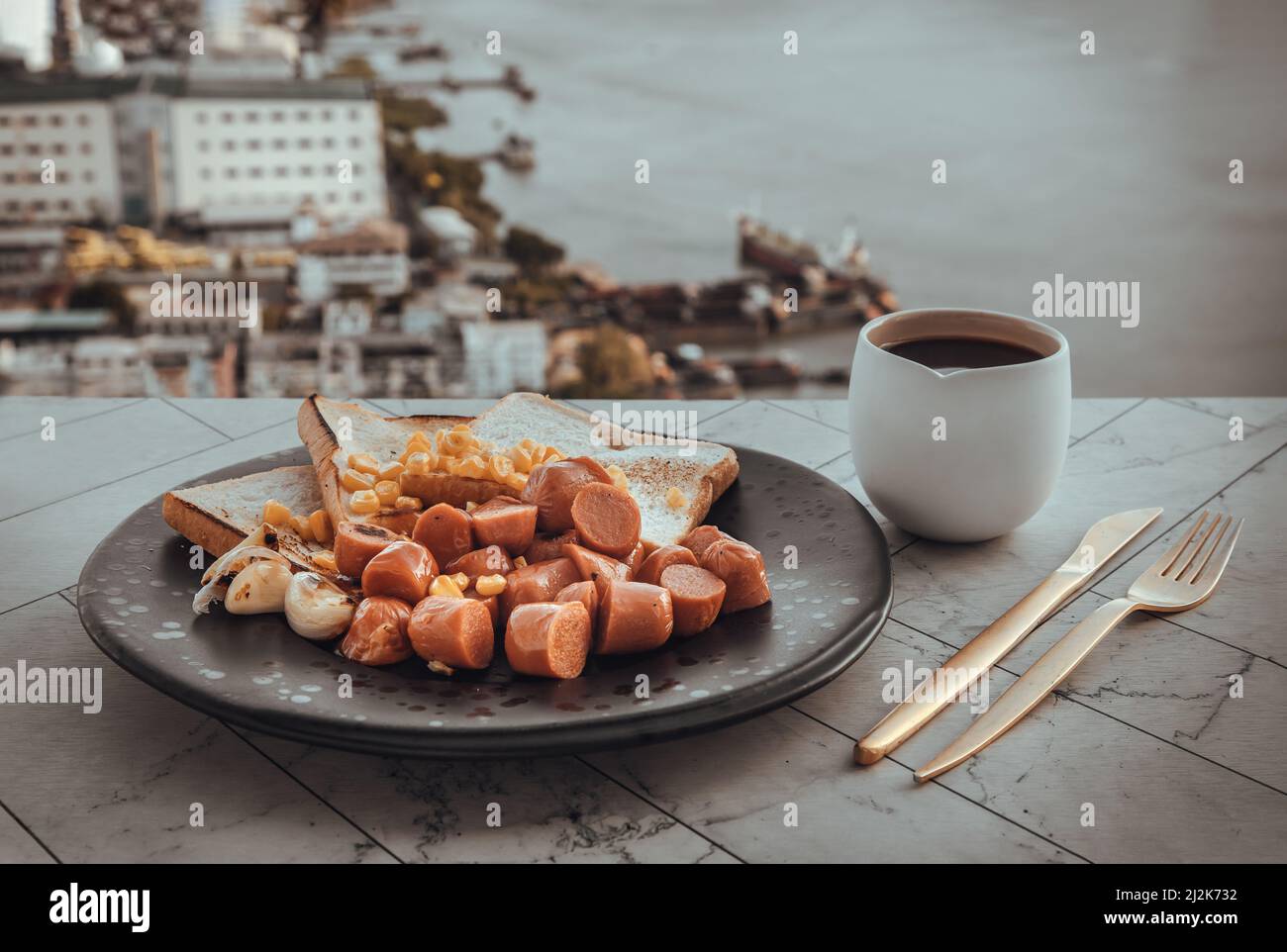 Breakfast with Fried sausages, Breads, Sweet corn kernels and Garlic on Black ceramic plate served with Cup of Black coffee. Selective focuse. Stock Photo