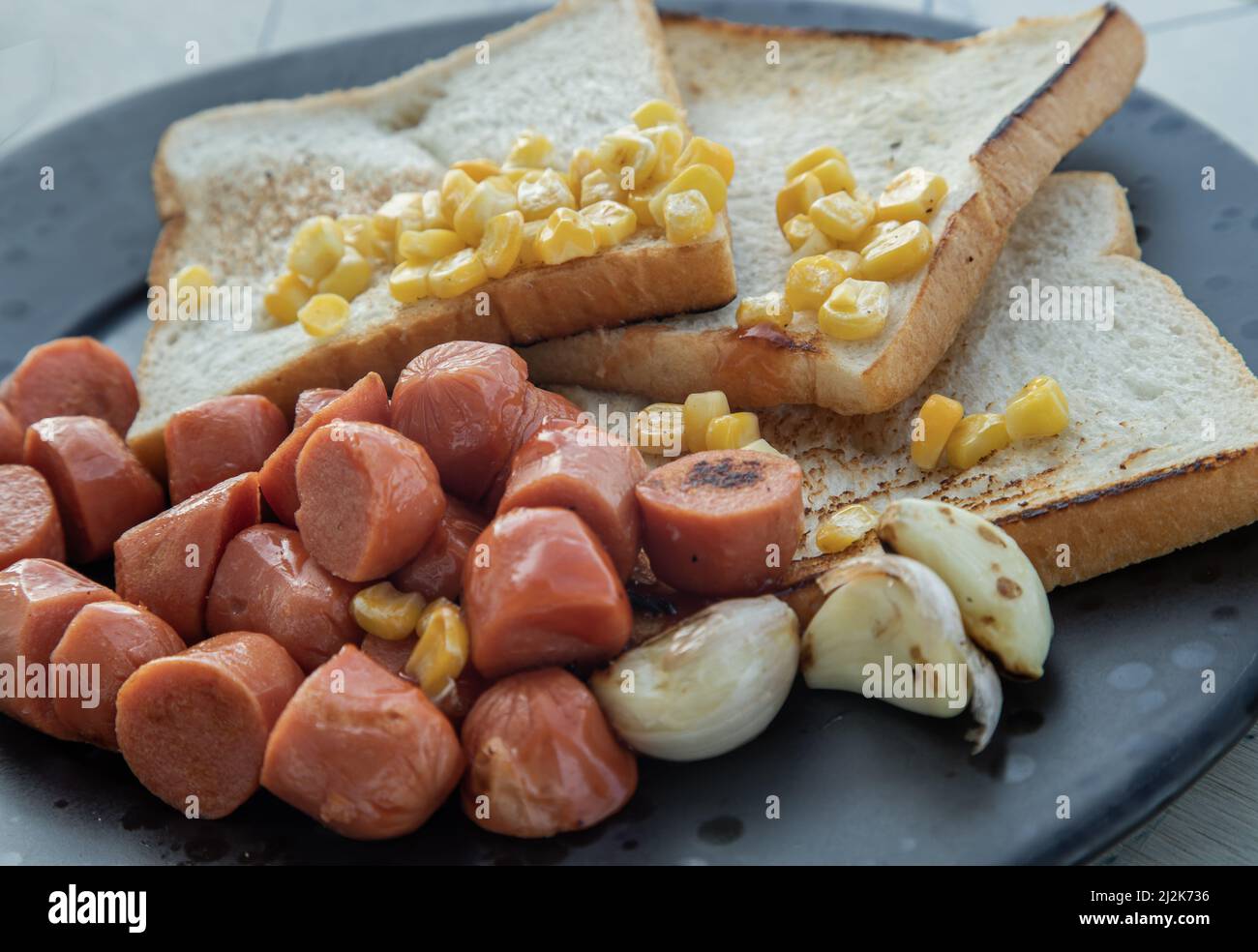 Close-up of breakfast with Fried sausages, Breads, Sweet corn kernels and Garlic. Selective focuse. Stock Photo