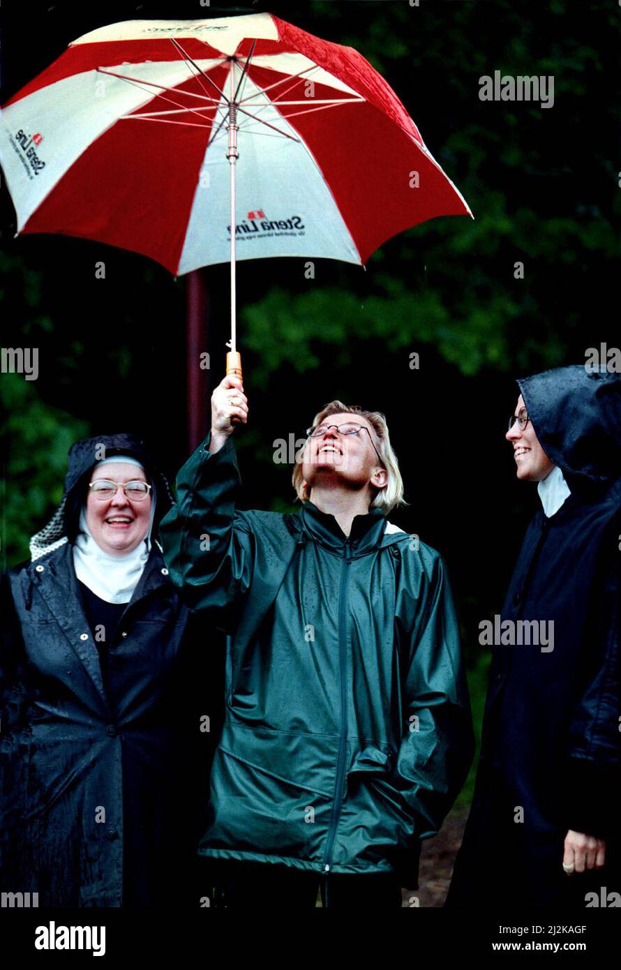Minister for the Environment Anna Lindh thought that the visit to Ombergsliden, south of Vadstena, Sweden, was rewarding despite the rain. The gates of heaven opened and Anna Lindh had to protect the sisters Katarina and Anna from the Mariadöttrarna with an umbrella. Stock Photo