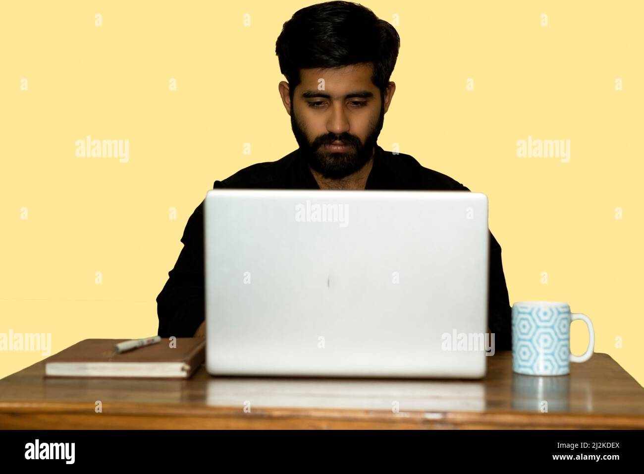 Work From Home. A man working on laptop. A coffee mug and diary kept on side. selective focus. Stock Photo