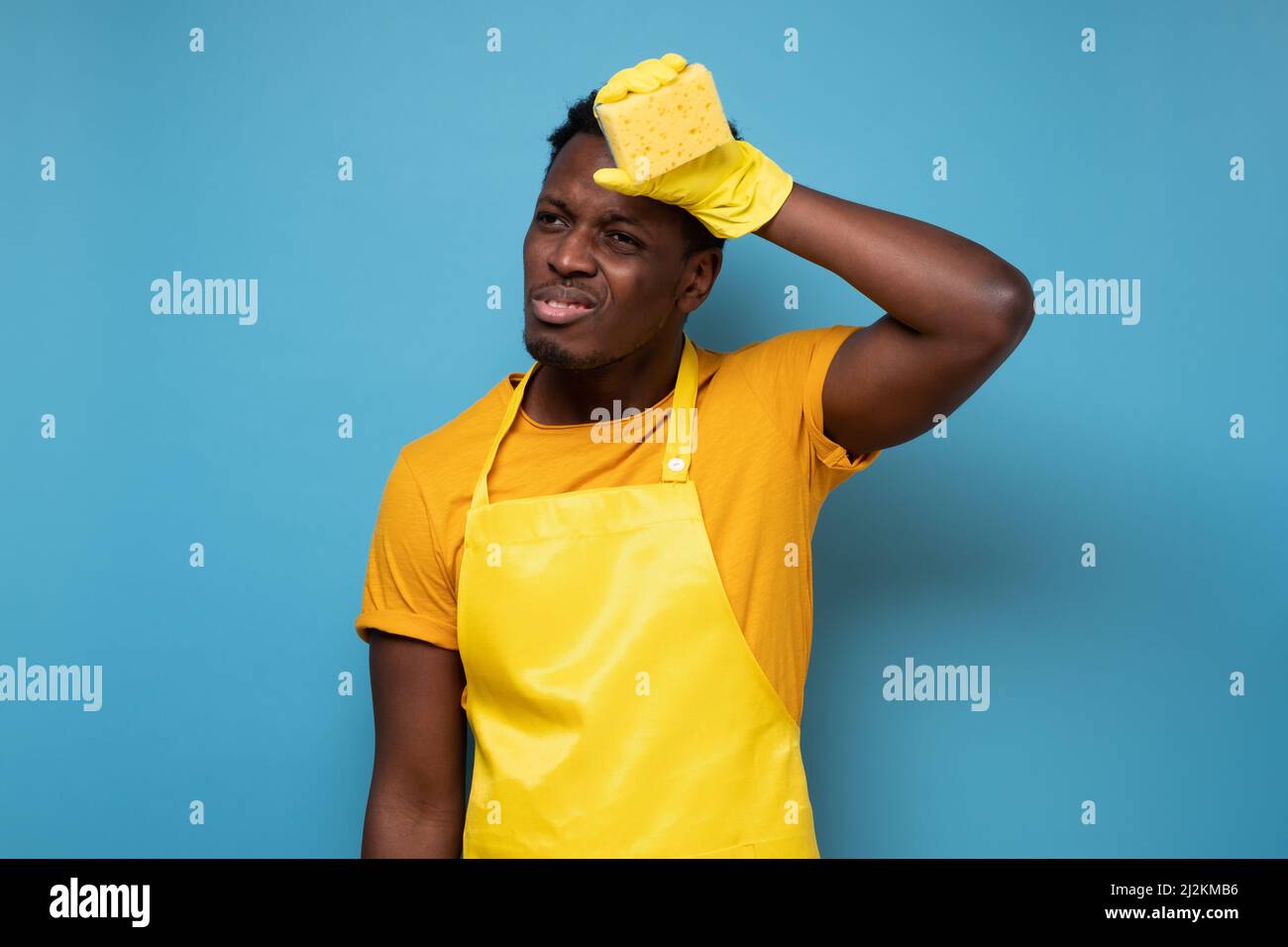 Tired young african man wearing yellow rubber gloves for hands