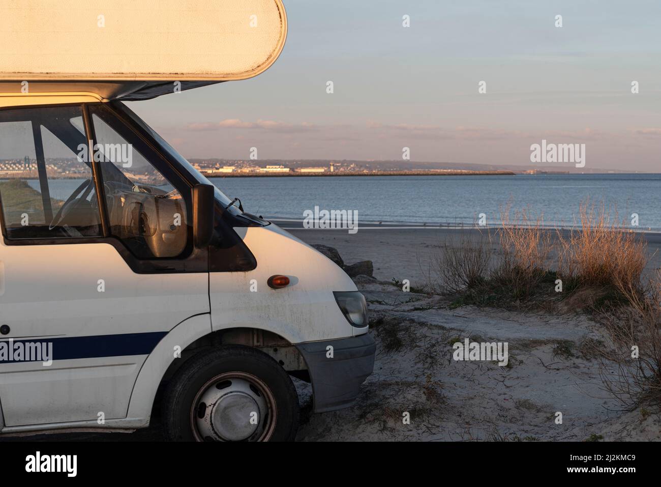 A camper van parked by the beach and the sea to spend the night Stock ...