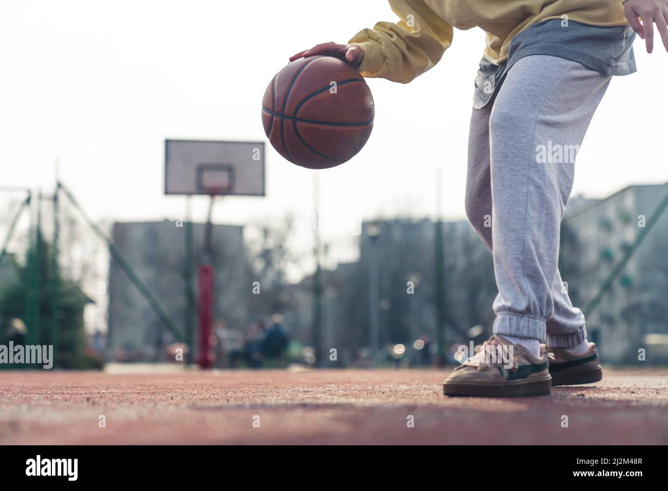 Young Caucasian woman plays basketball on the sports field alone , ball, hands and legs are visible, game process concept copy space . High quality photo Stock Photo