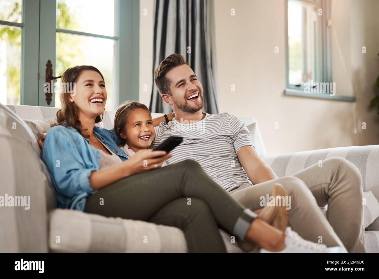 Little girl with toy bear changing TV channels by remote control on sofa at  home Stock Photo - Alamy