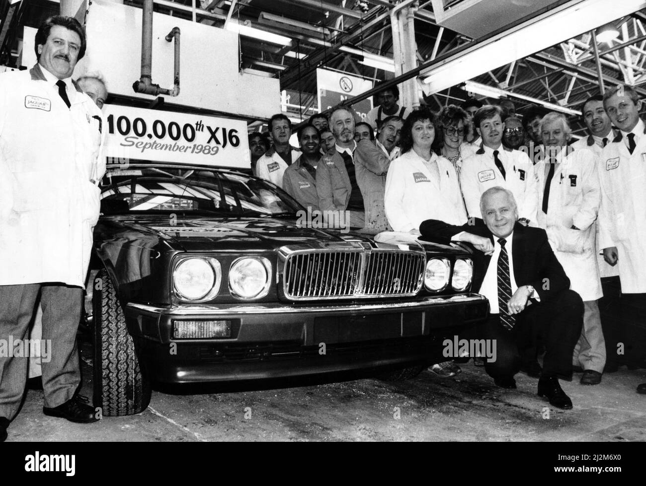 Jaguar Chairman and Chief Executive Sir John Egan at the front of the 100,000th XJ6 off the production line, surrounded by assembly worker. 11th September 1989. Stock Photo