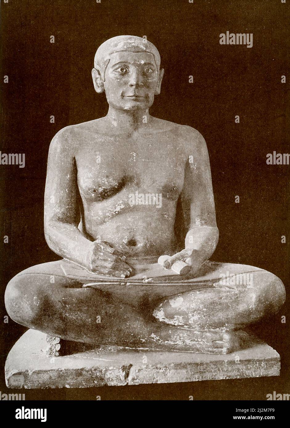 This limestone statue of a seated Egyptian scribe is housed in the Louvre Museum in Paris. The sculpture of the Seated Scribe or Squatting Scribe is a well-known piece of ancient Egyptian art. It represents a figure of a seated scribe at work. Discovered in 1850 at Saqqara, north of the alley of sphinxes leading to the Serapeum of Saqqara, it has been dated to the period of the Old Kingdom, from either the 5th Dynasty, c. 2450–2325 BC or the 4th Dynasty, 2620–2500 BC. Stock Photo