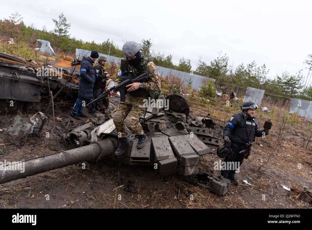 Ukrainian service members inspect a destroyed Russian tank with a dead