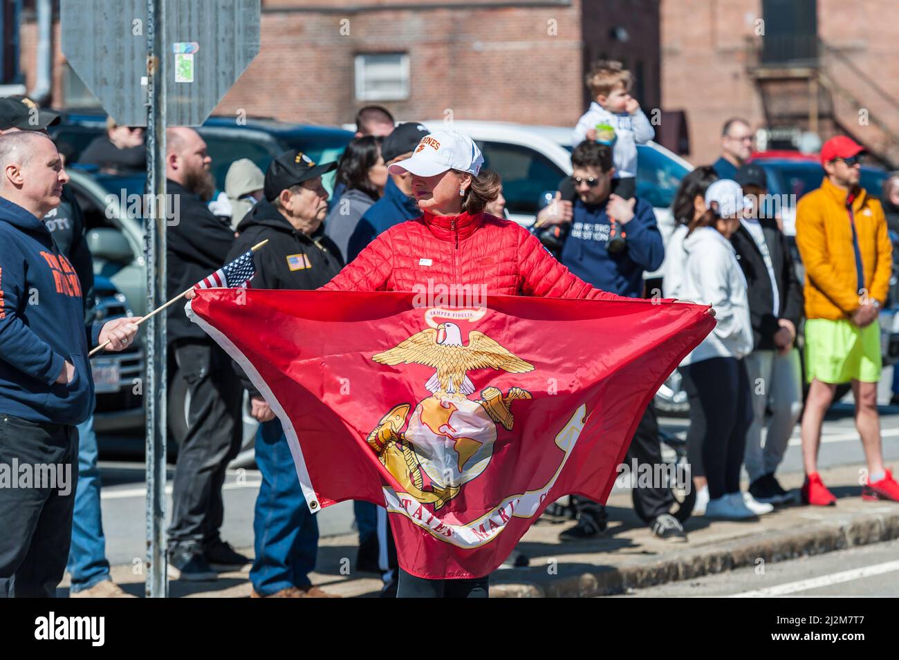 Woman holding a US Marines flag at procession for fallen USMC CPT Ross Reynolds, returning to hometown of Leominster, Massachusetts Stock Photo