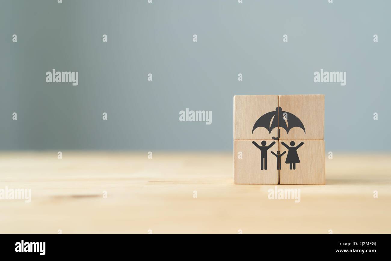 Family life and health insurance concept.  Wooden cubes with symbol; family under the umbrella standing on the table with the beautiful grey backgroun Stock Photo