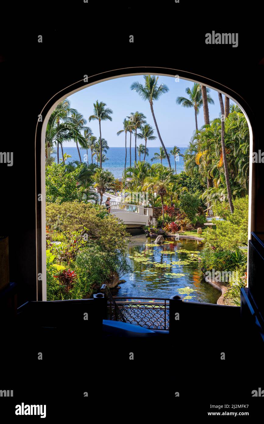 A framed archway garden view looking over the koi pond to palm trees and the Pacific Ocean at the The Fairmont Kea Lani Maui Resort, Wailea, Maui, Haw Stock Photo