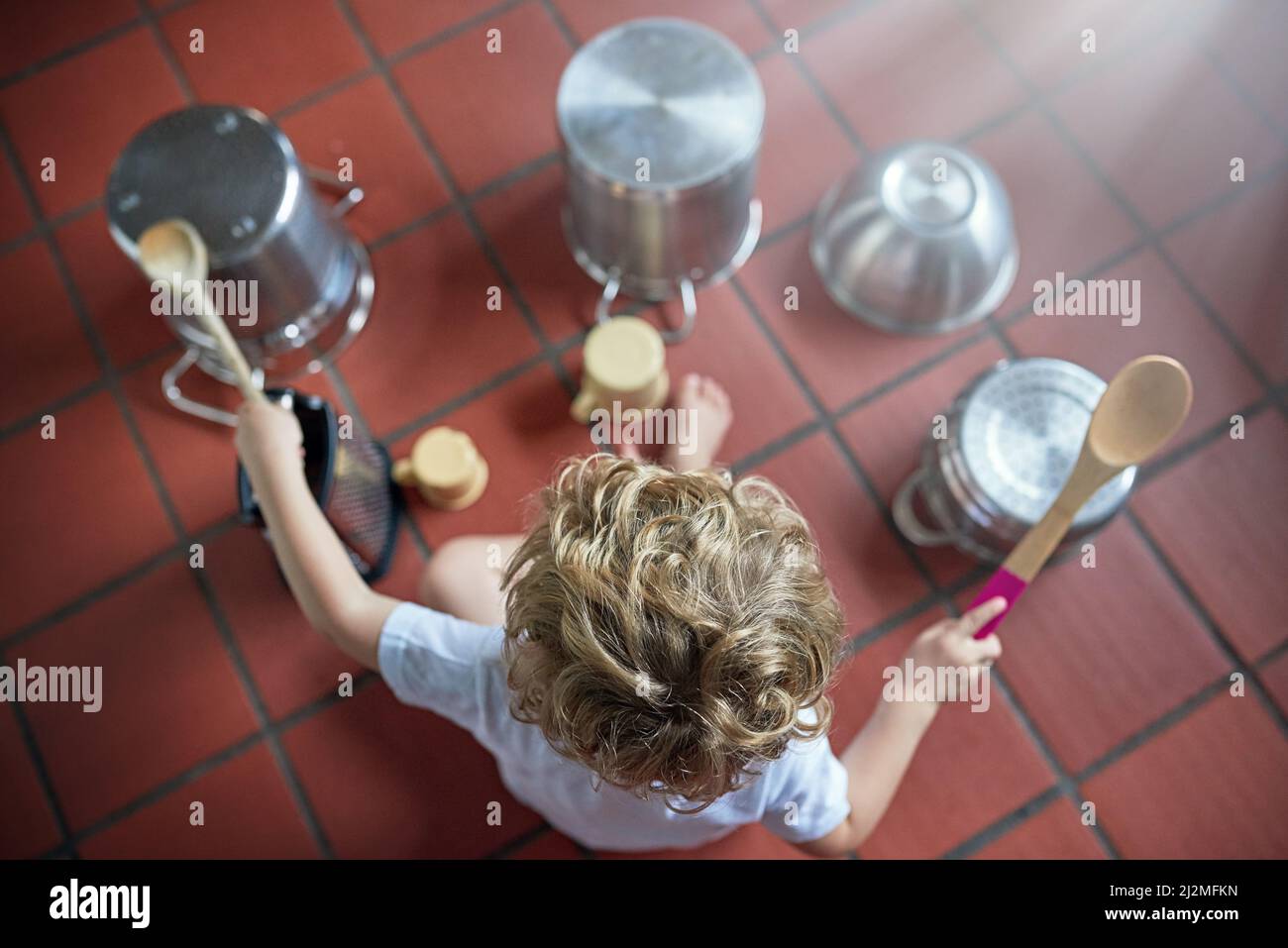 Showing off his drumming skills. High angle shot of an adorable little boy playing drums on a set of pots in the kitchen. Stock Photo