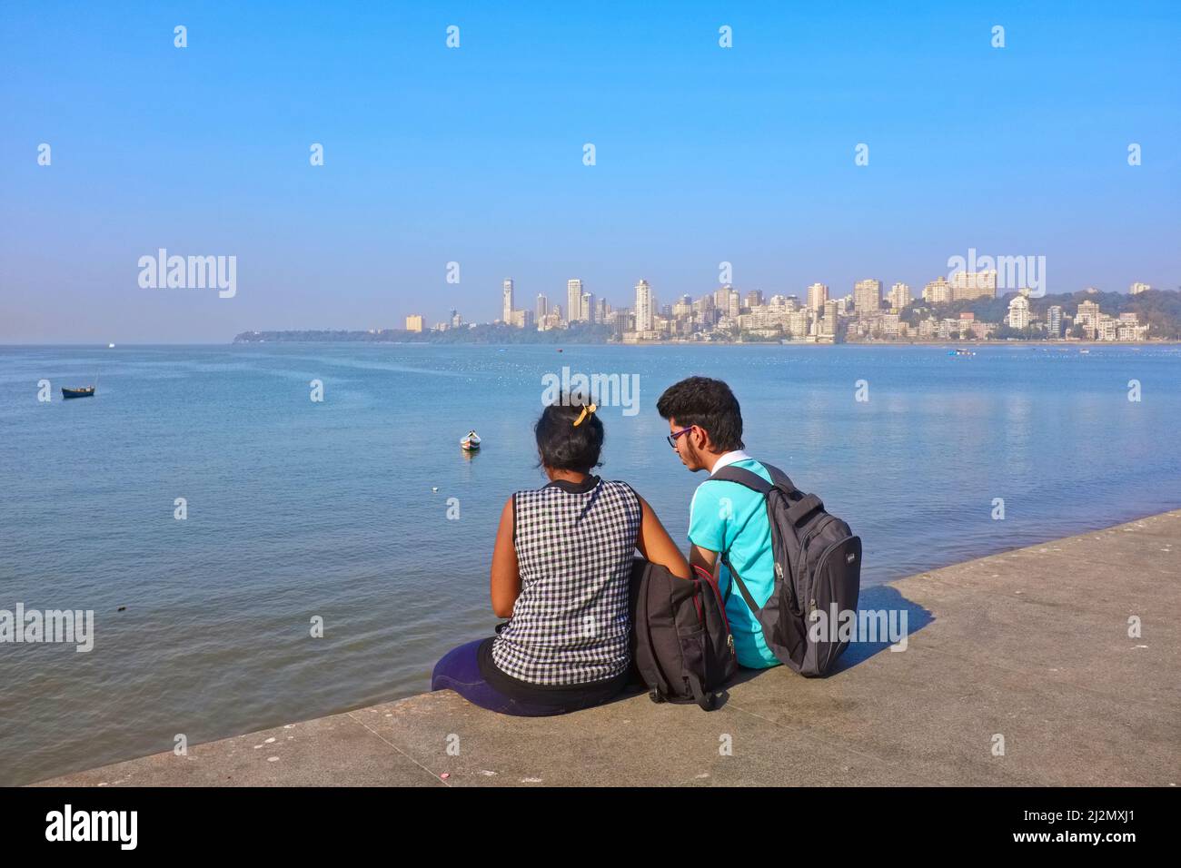 A teenage couple enjoy the view from the embankment of Marine Drive by the Arabian Sea and near Chowpatty Beach; Girgaum area, Mumbai, India Stock Photo