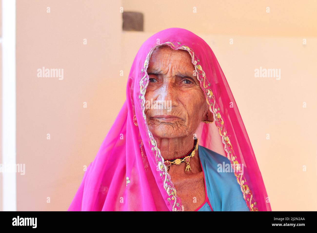 Pali Rajasthan , India - October 23, 2021. Close-up portrait photo of An indian elderly woman sitting in a pinkish red veil. Indian village Stock Photo