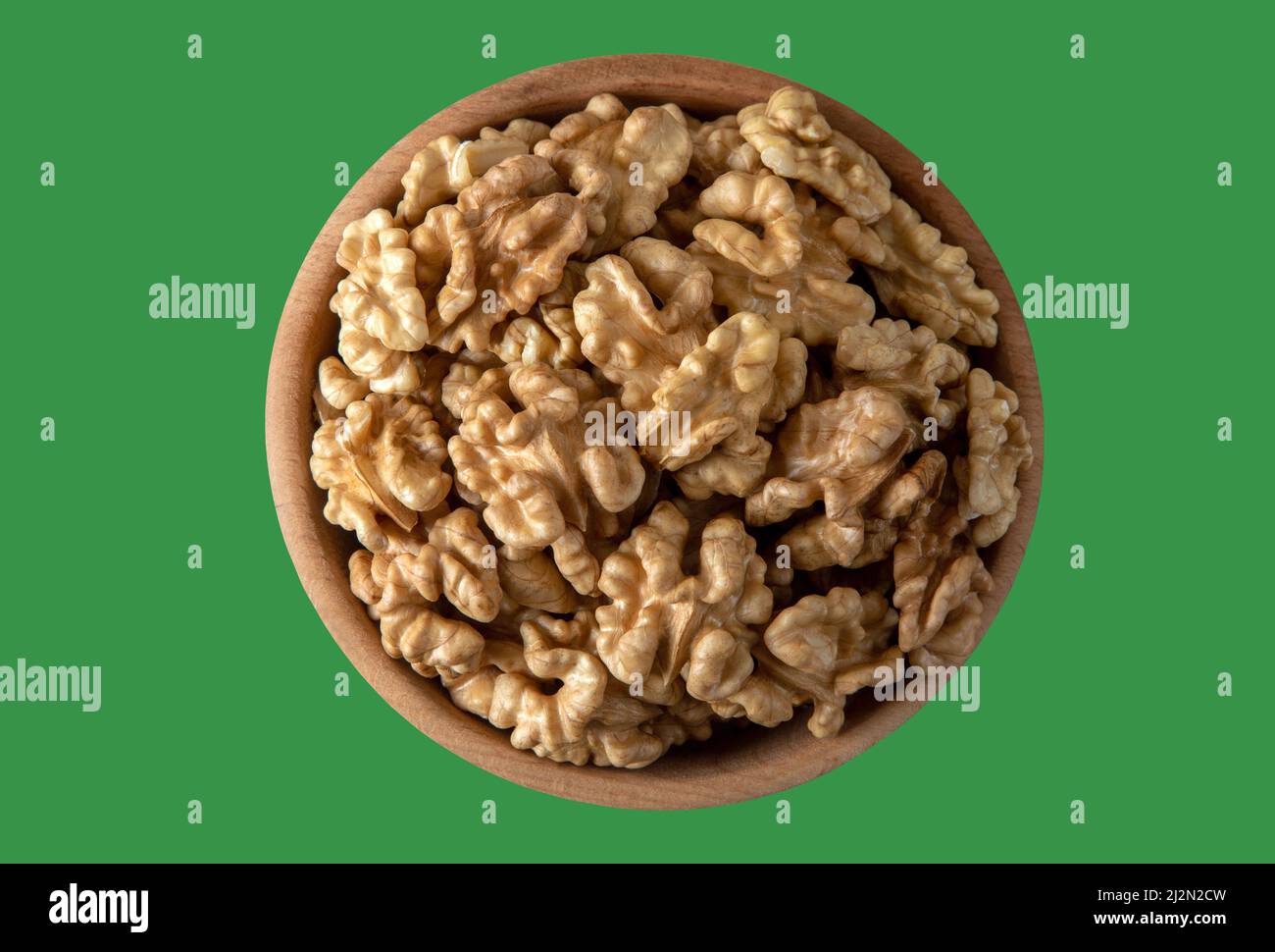 Bowl full of peeled walnuts on a green background,top view Stock Photo