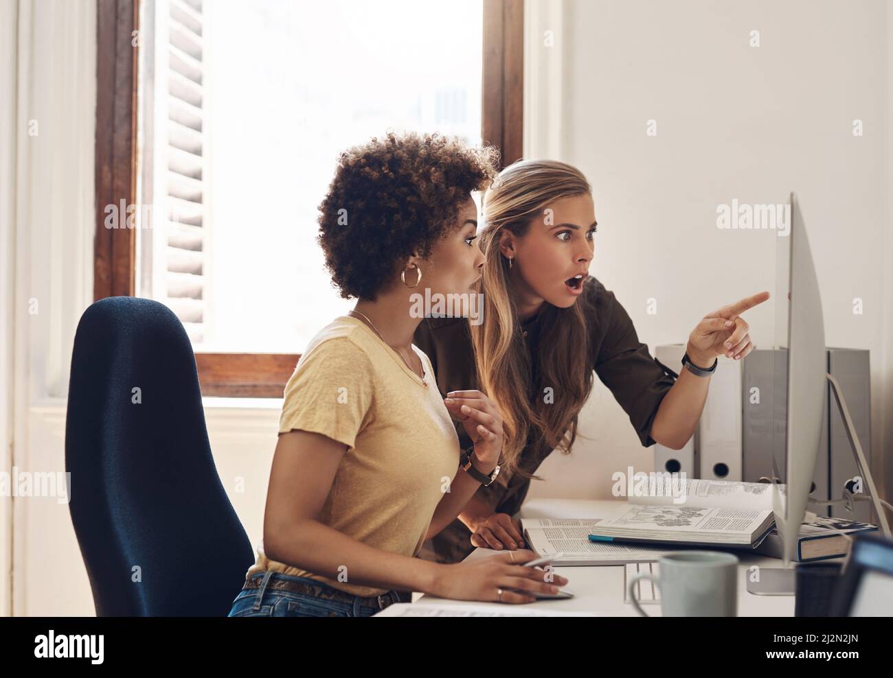 Are you seeing this too. Shot of two businesswomen looking surprised while working together on a computer in an office. Stock Photo