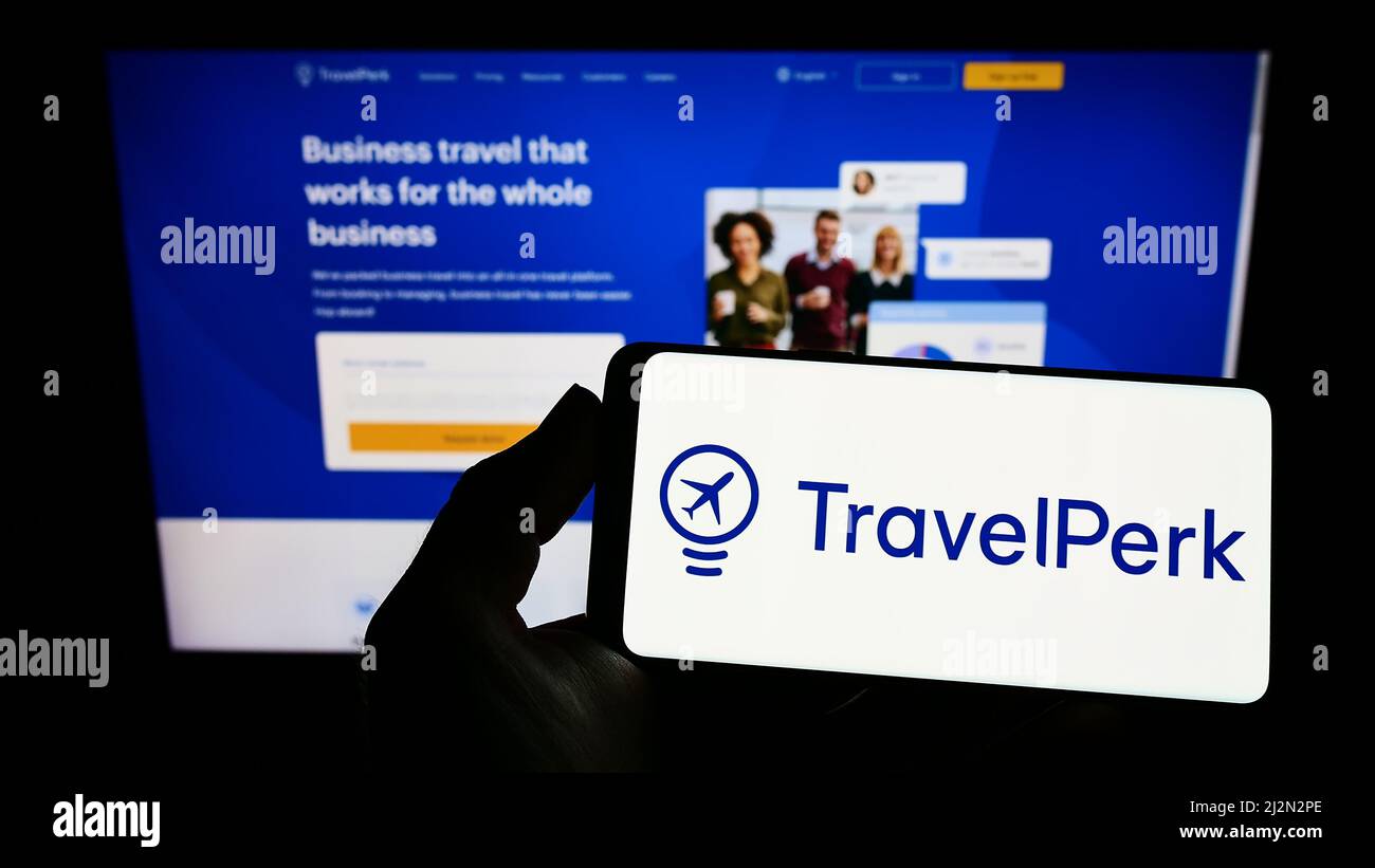Person holding smartphone with logo of Spanish software company TravelPerk S.L.U on screen in front of website. Focus on phone display. Stock Photo
