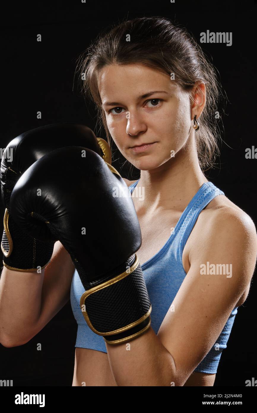 Pretty Muay Thai female boxer in attack pose. Fitness young woman