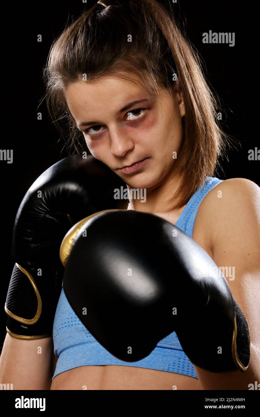 Pretty Muay Thai female boxer with bruise on face in attack pose