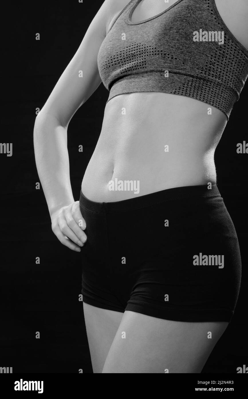 slim muscular woman in sportswear posing in studio on black background monochrome Stock Photo