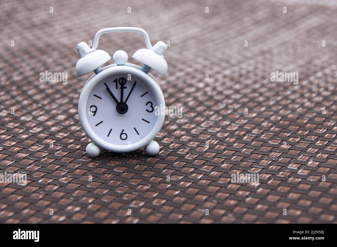 White alarm clock on pool chair. The clock set at 11 o'clock. Morning and deadline concept. Stock Photo