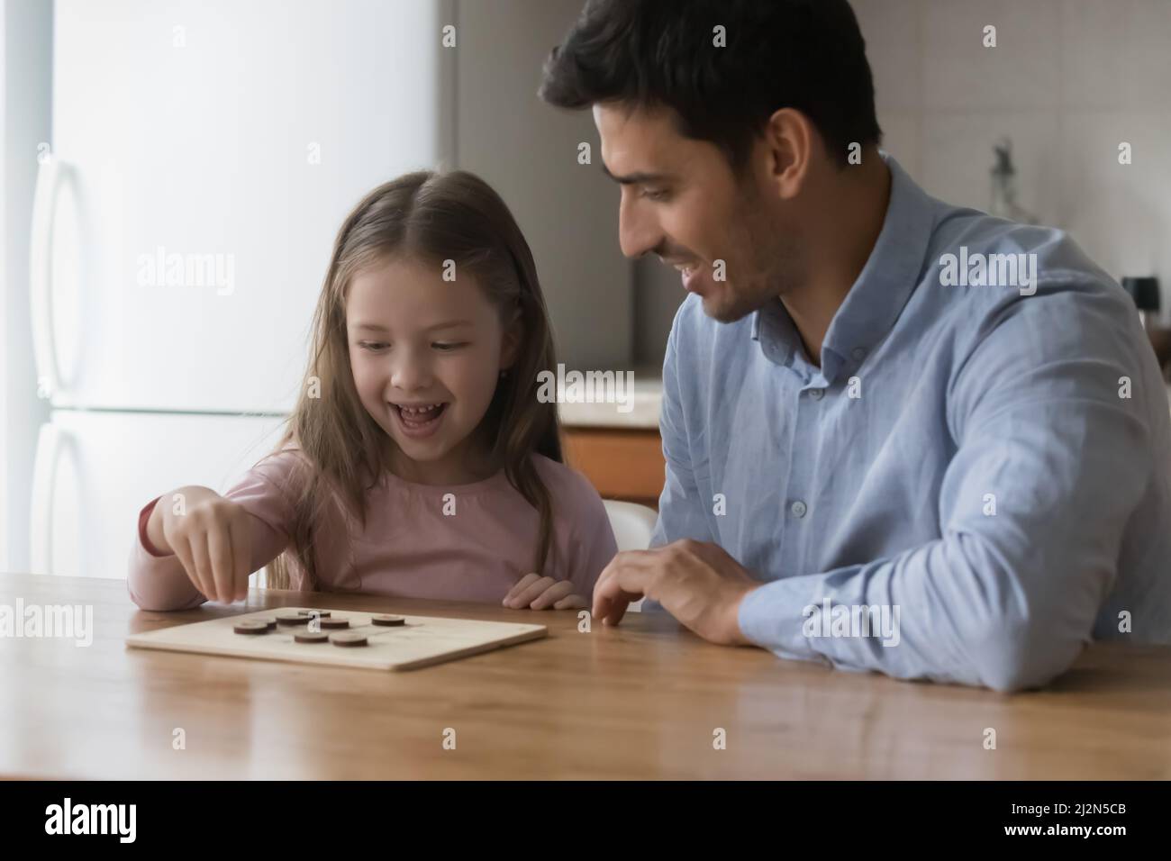 Happy preschool daughter kid and handsome dad playing board game Stock Photo