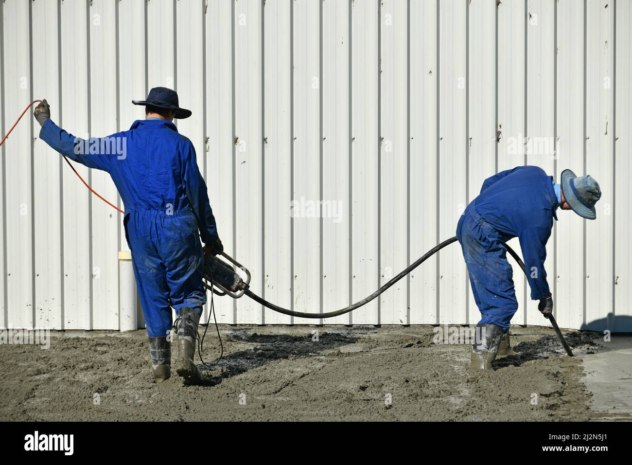 builders use a vibrator to settle newly poured cement Stock Photo