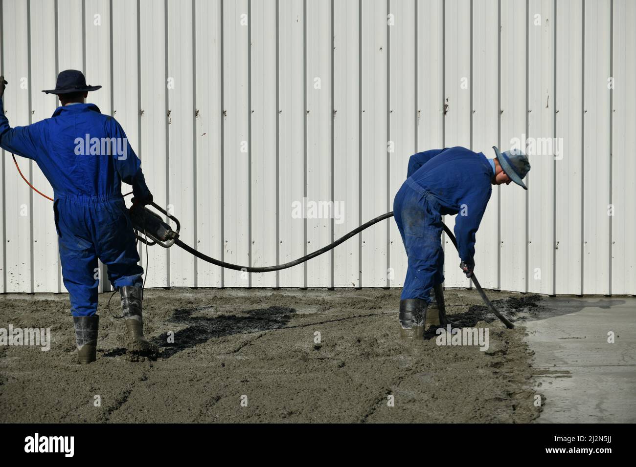 builders use a vibrator to settle newly poured cement Stock Photo