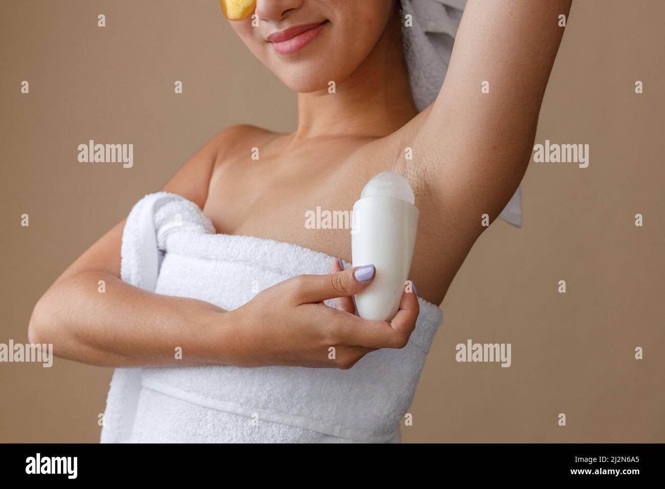 Young woman applying antiperspirant on armpit after shower Stock Photo