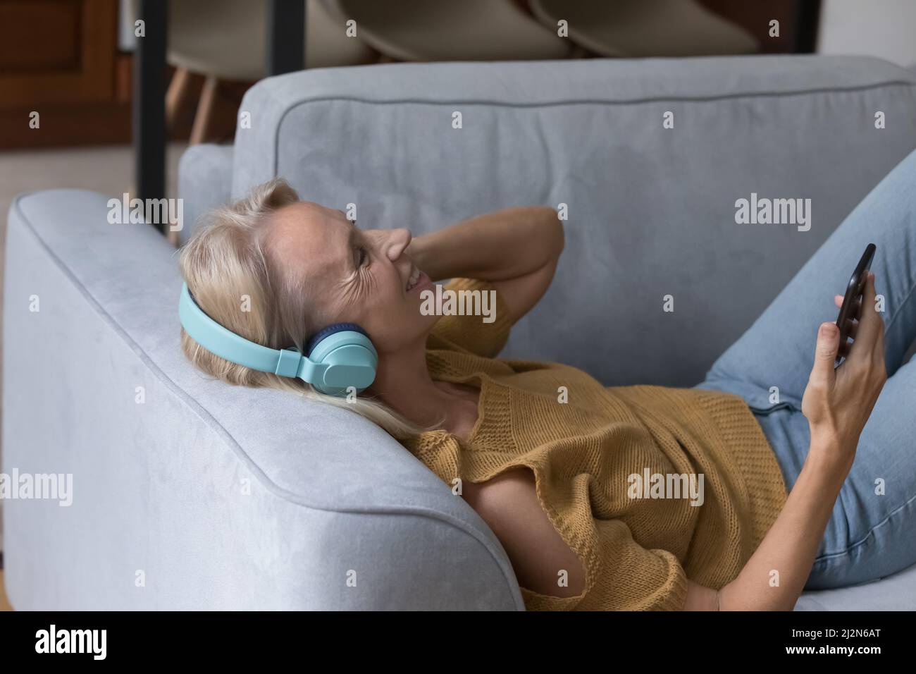 Happy middle aged woman in wireless headphones listening to music Stock ...