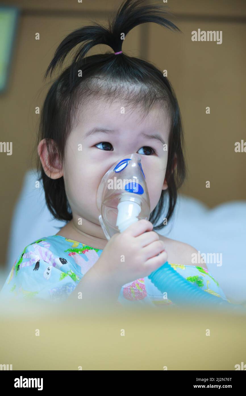Cute asian child holds a mask vapor inhaler for treatment of asthma on