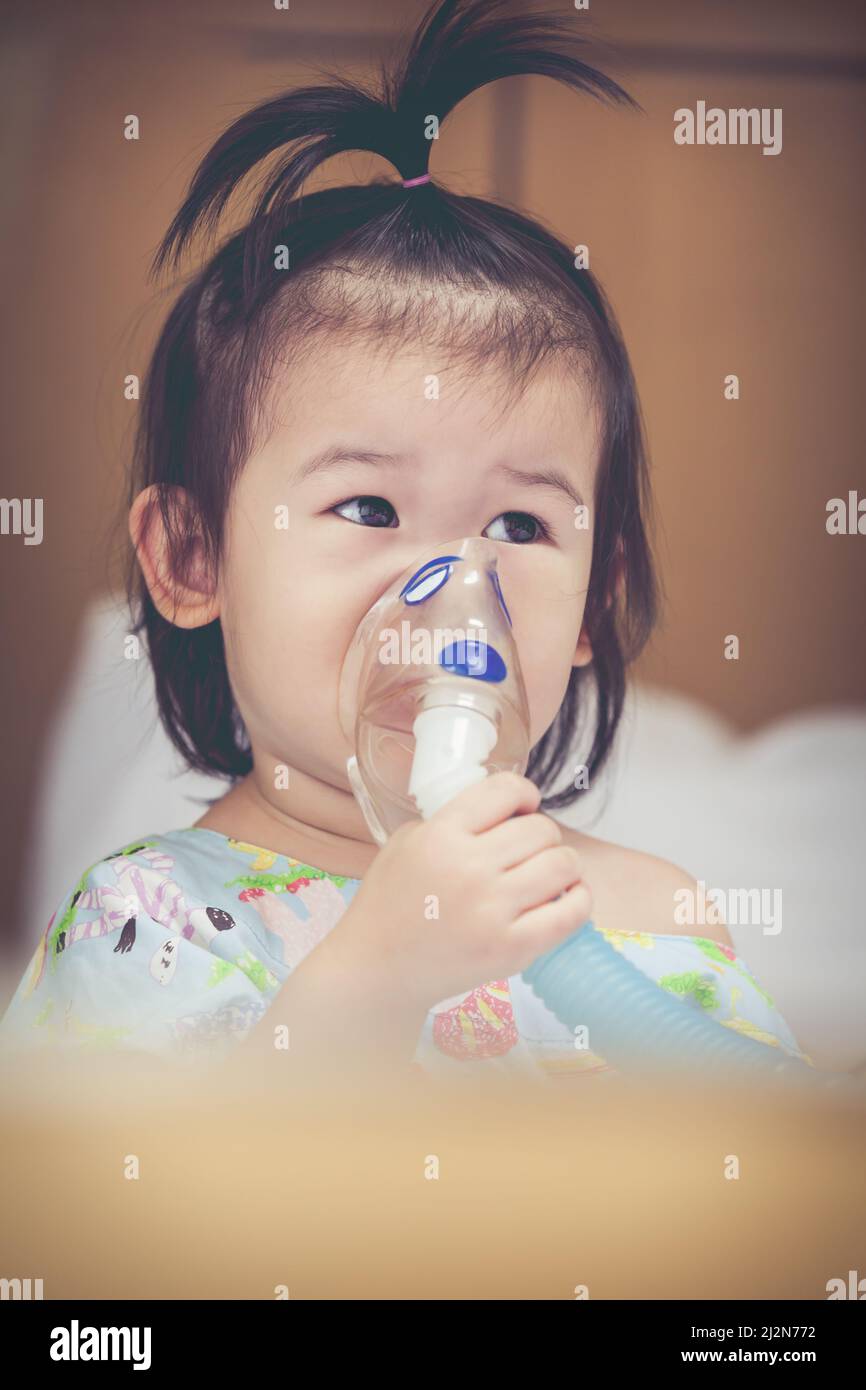 Cute asian child holds a mask vapor inhaler for treatment of asthma on ...