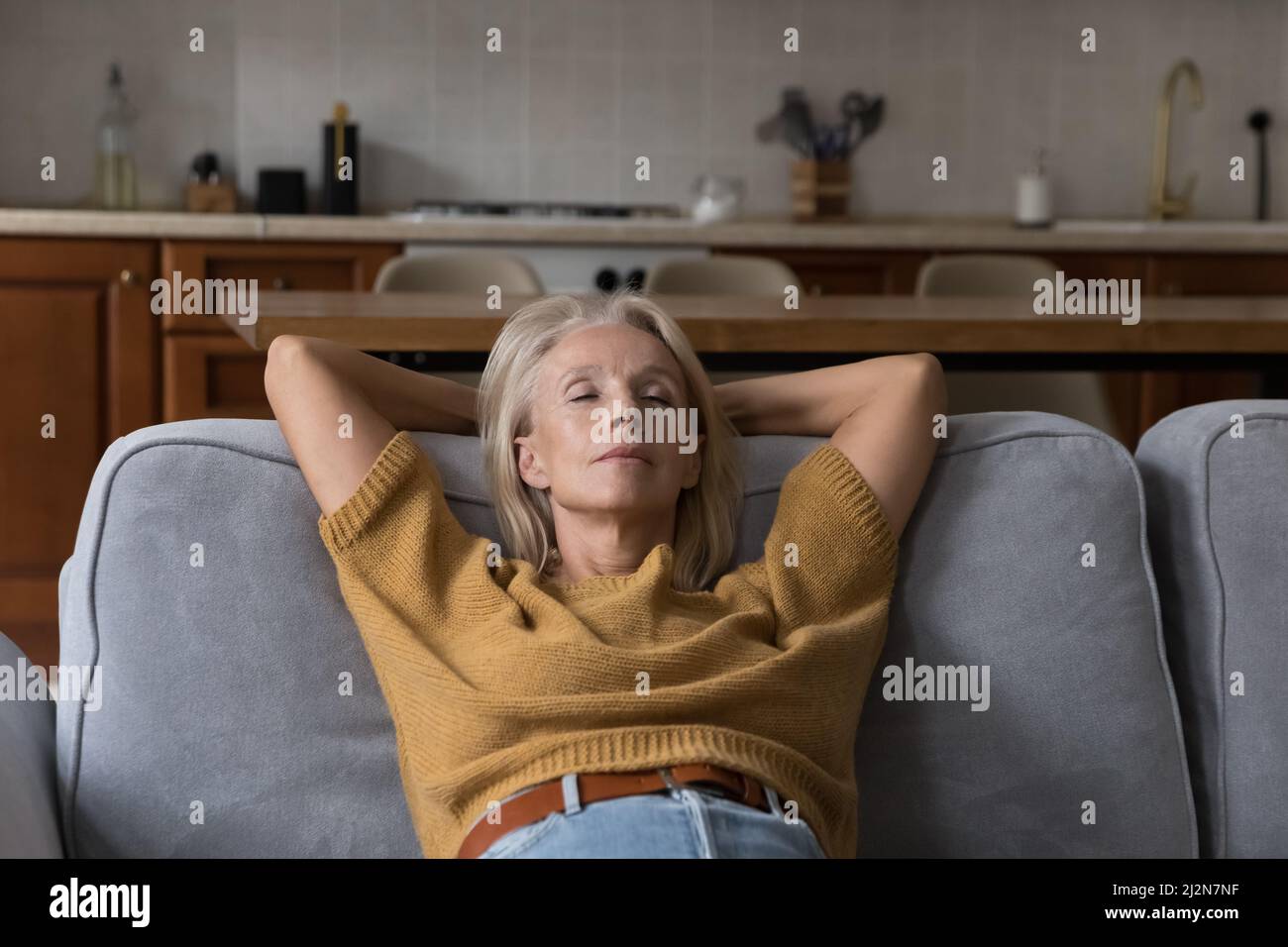 Calm elder lady relaxing with closed eyes on sofa Stock Photo