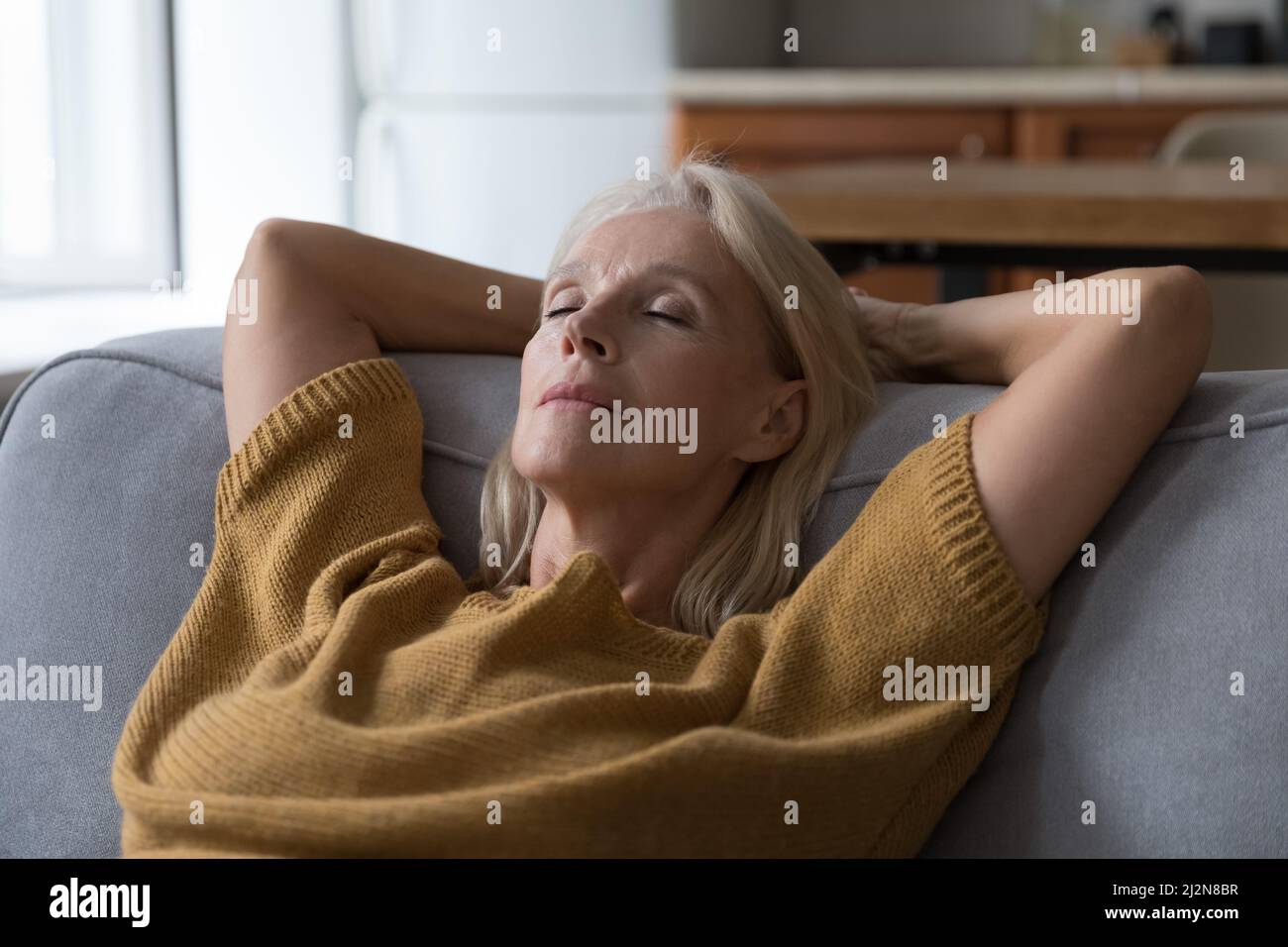 Peaceful middle aged woman resting on sofa with closed eyes Stock Photo