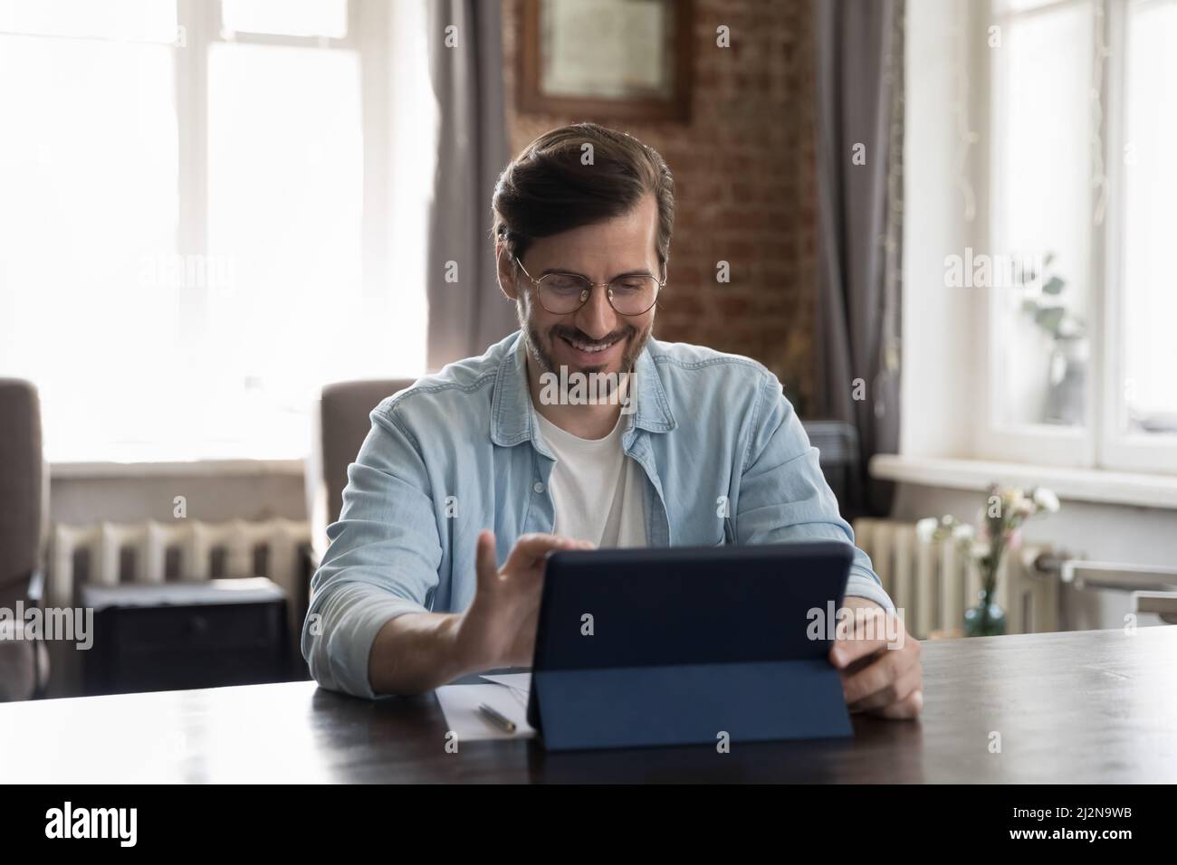 Happy millennial businessman in casual using tablet computer Stock Photo