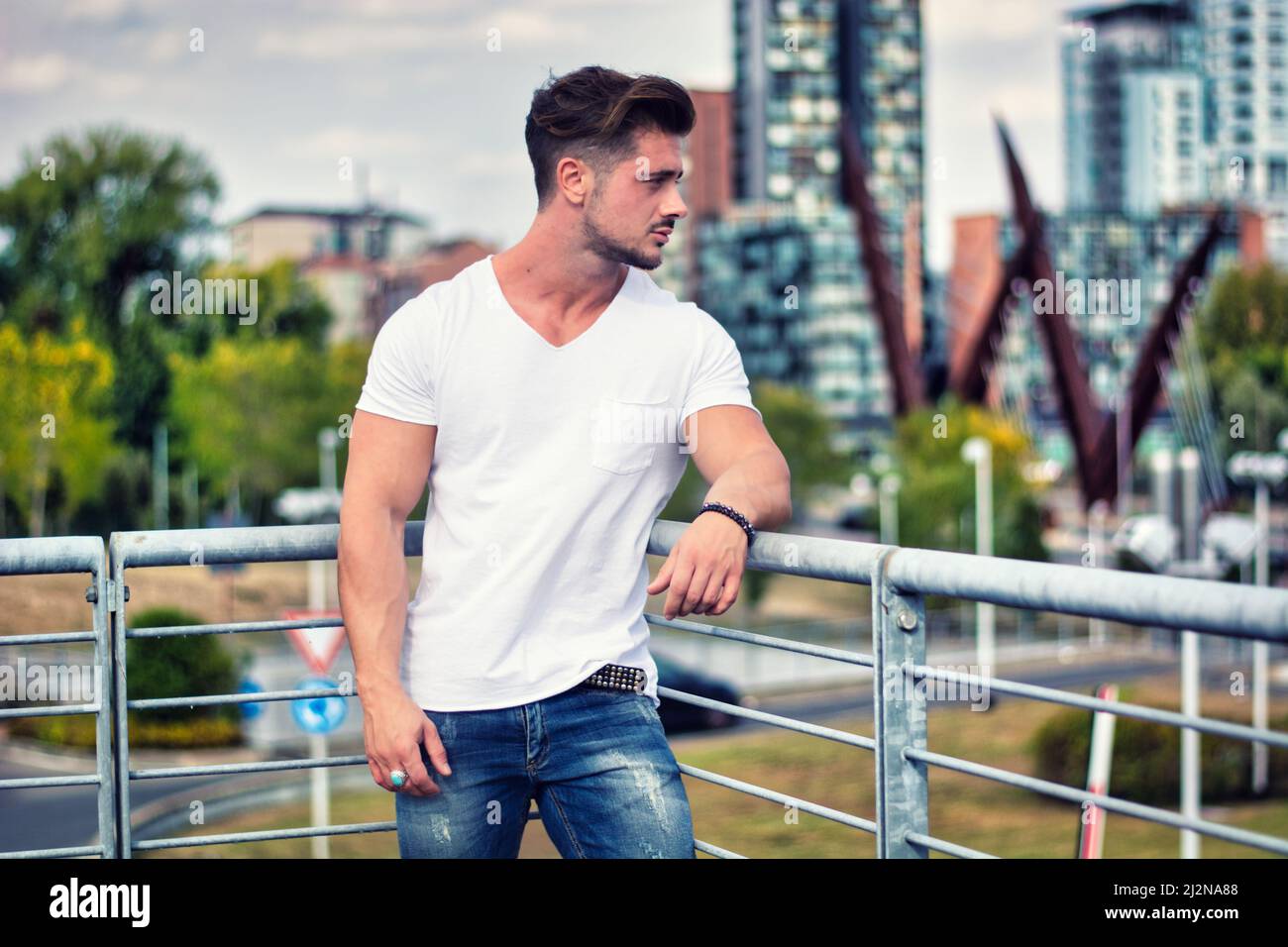 Handsome young man in white t-shirt outdoor in city setting Stock Photo