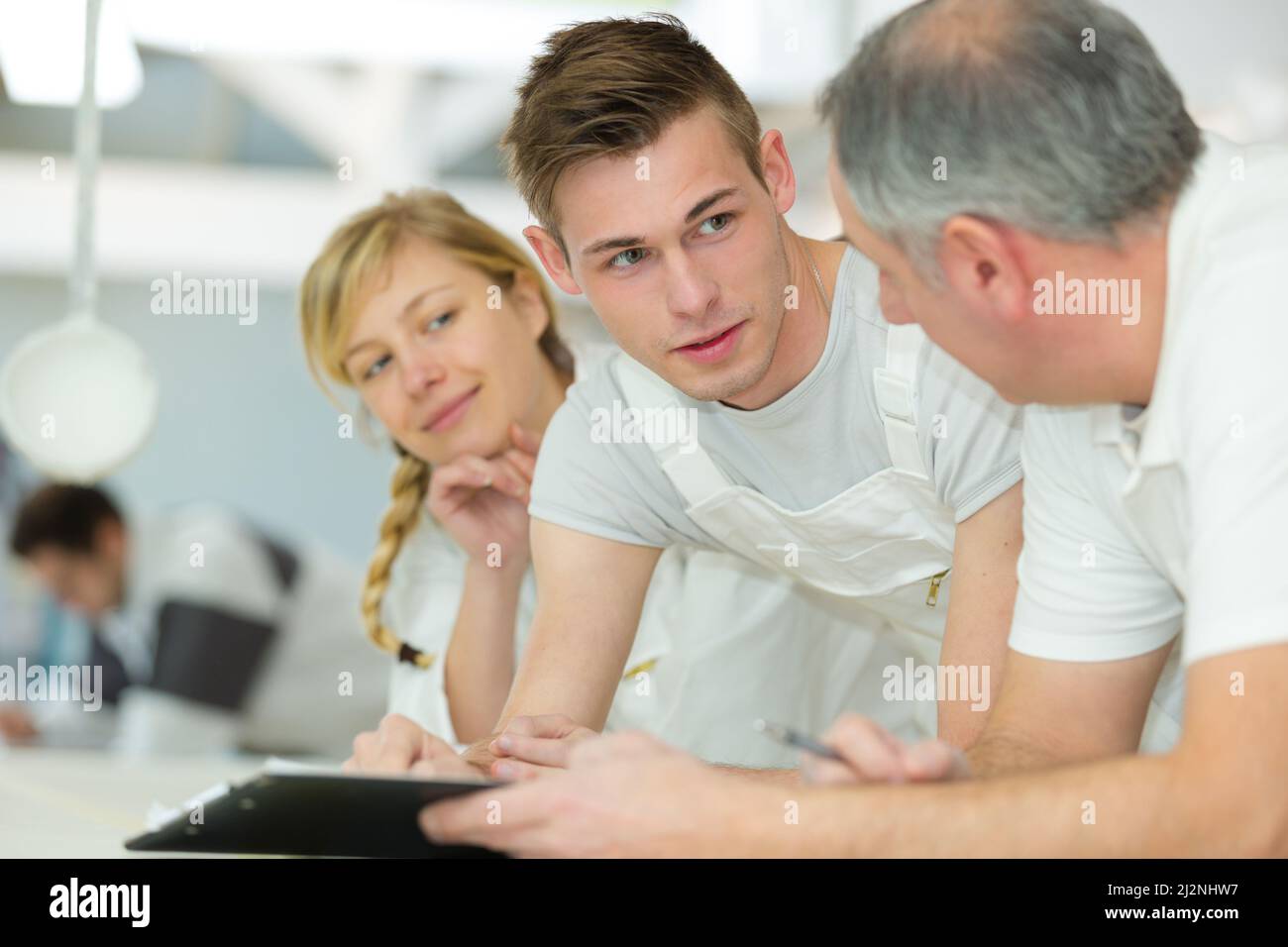 apprentice on jumper suits conversing with teacher Stock Photo