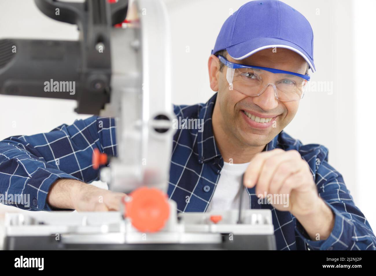 happy workman using circular saw in workshop Stock Photo
