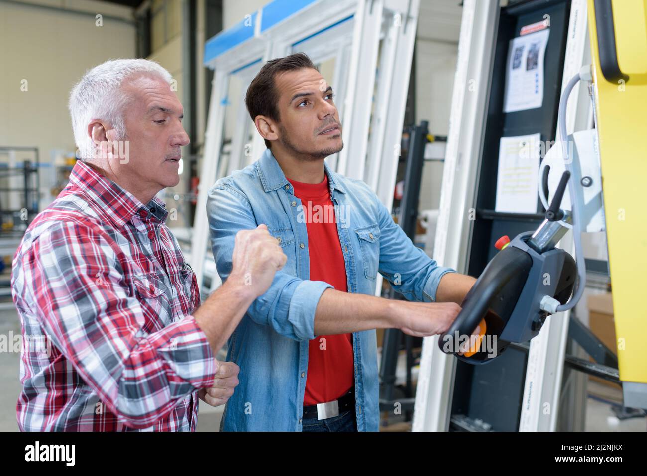 workmen operating controls in plastic window workshop Stock Photo