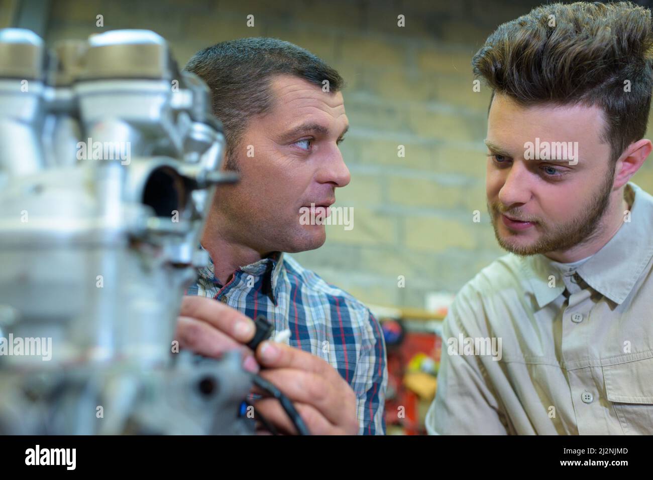 mechanic in onversation with his apprentice Stock Photo