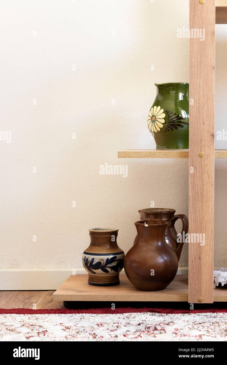 Different ceramic pottery vases on shelves, interior design Stock Photo
