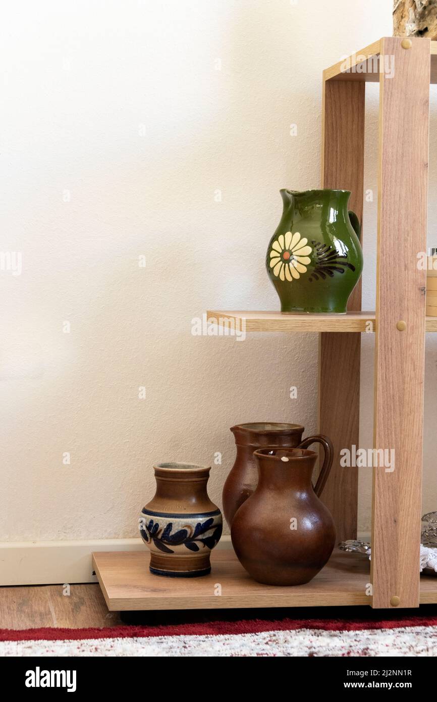 Different ceramic pottery vases on shelves, interior design Stock Photo