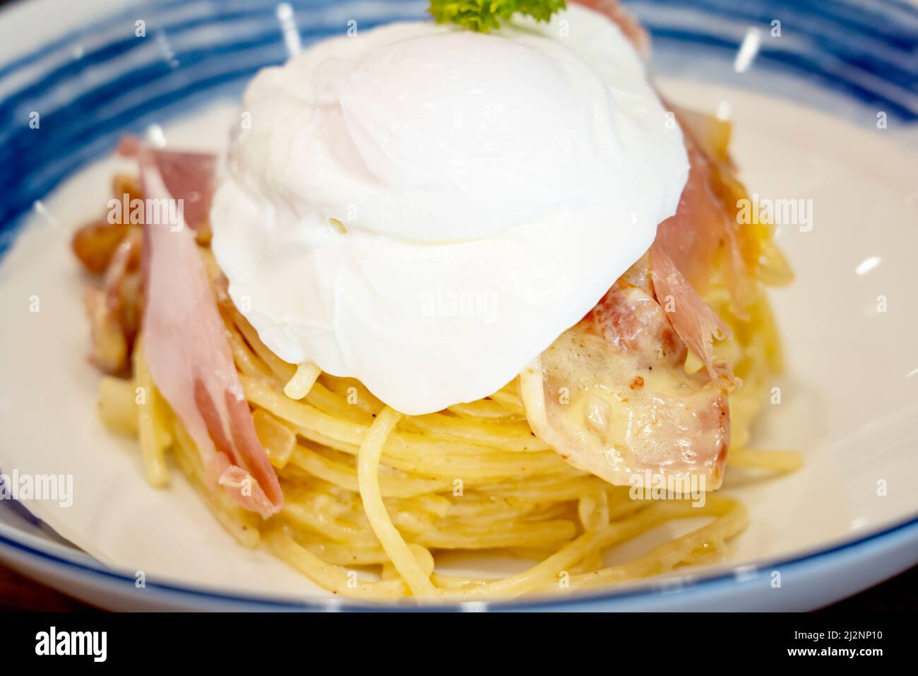 Egg yolk Pasta alla Carbonara. A fork spindles from a bowl of linguine