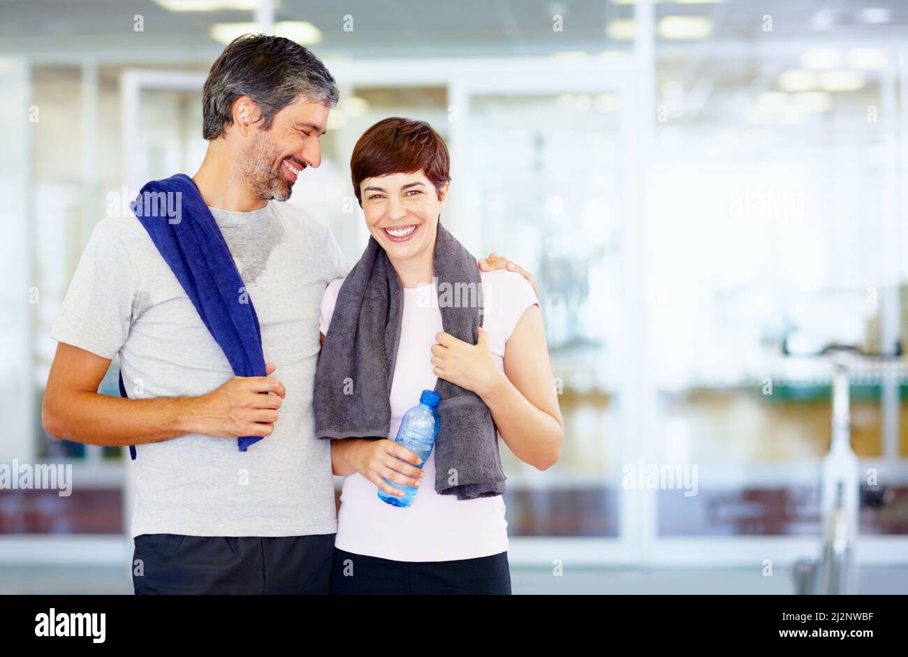 Fitness man and woman at fitness center. Portrait of fitness couple with arms around at gym. Stock Photo