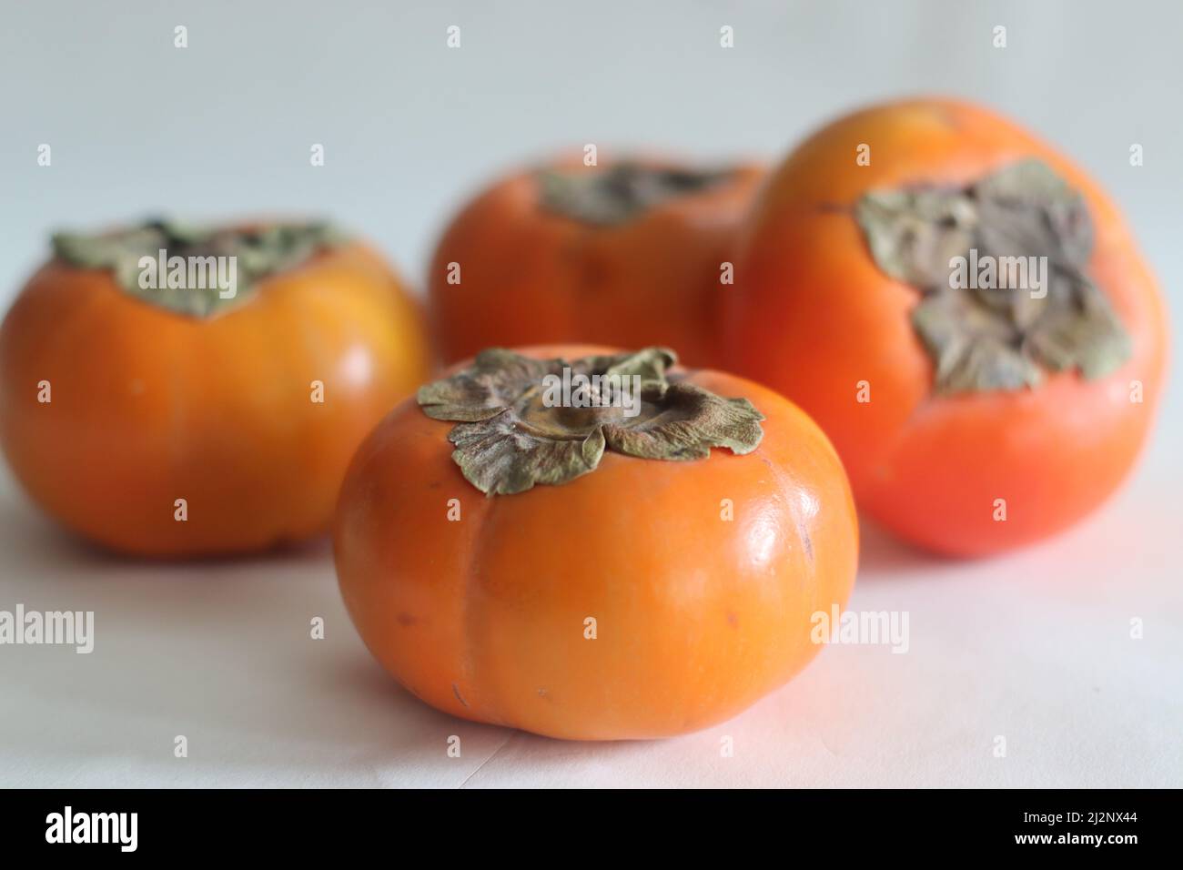 Persimmon or Amarphal is a fruit native to Japan, China, Korea, Burma, Nepal and in some parts of India. Deep orange colour fruit with sweet and sligh Stock Photo