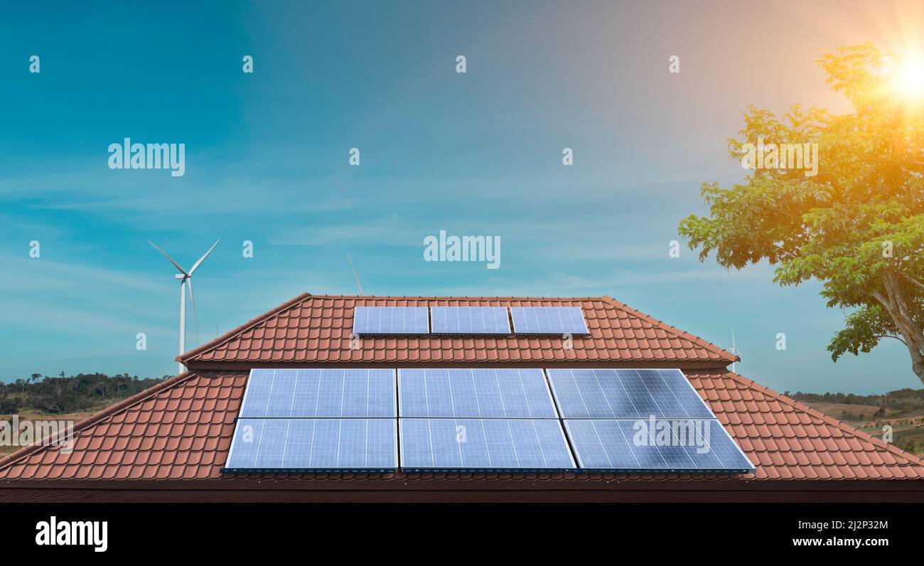 Solar panel on a roof of a house with wind turbines around ...