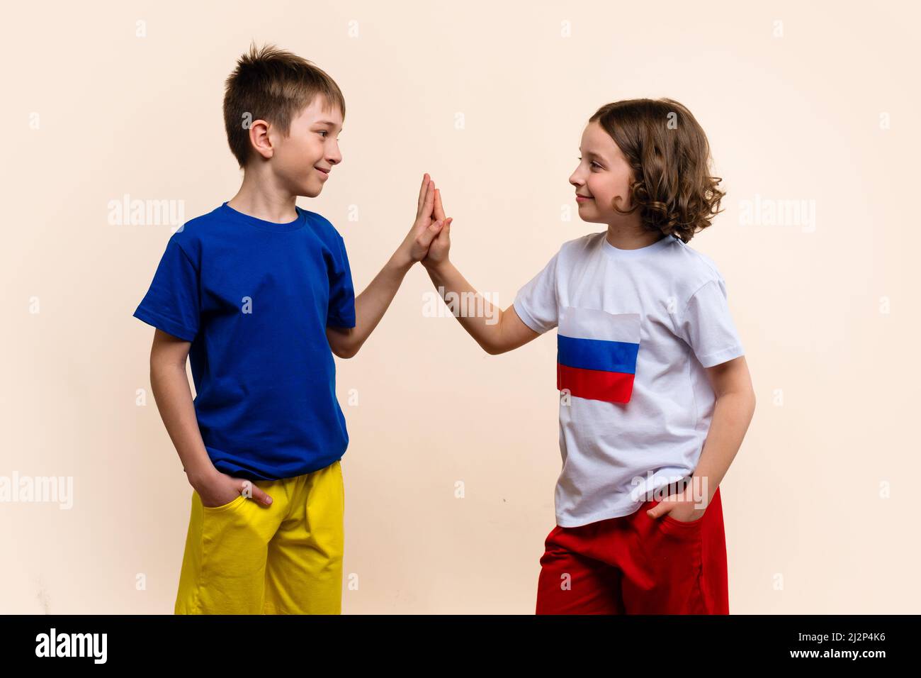 Boy and Girl in Outfits in Colors Flags Russia and Ukraine Look Each Other, Giving High Five and Agree on Truce. Concept Successful Negotiations to Peace-making. Friendship of Fraternal Peoples Stock Photo
