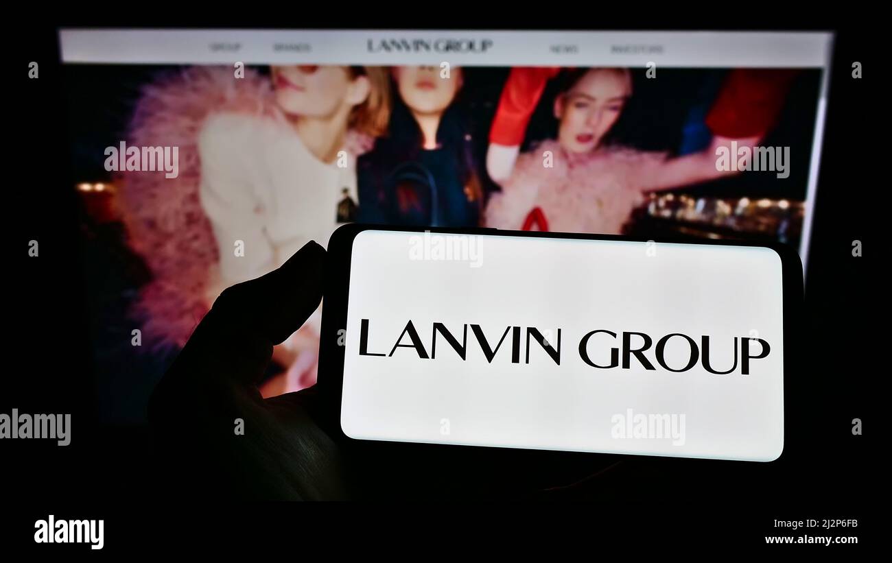 Person holding cellphone with logo of Chinese fashion company Lanvin Group on screen in front of business webpage. Focus on phone display. Stock Photo