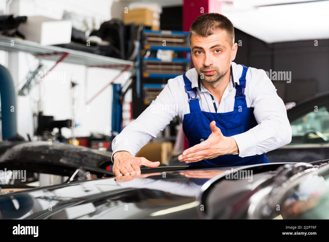 Male worker showing car after repainting Stock Photo