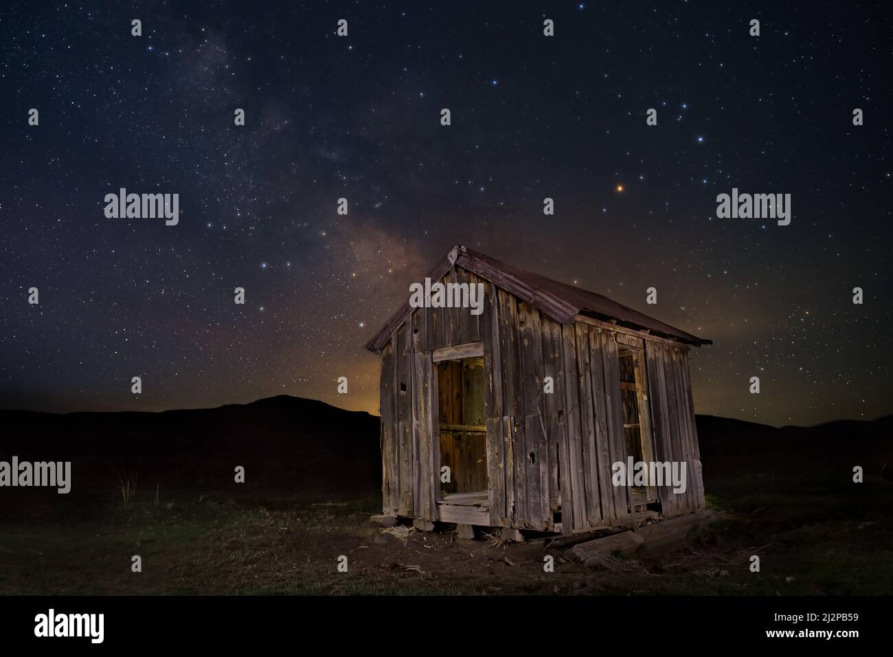 Abandoned shack un the high desert of Lassen County California USA.  Photographed under the galactic core of the Milky Way during morning twilight. Stock Photo