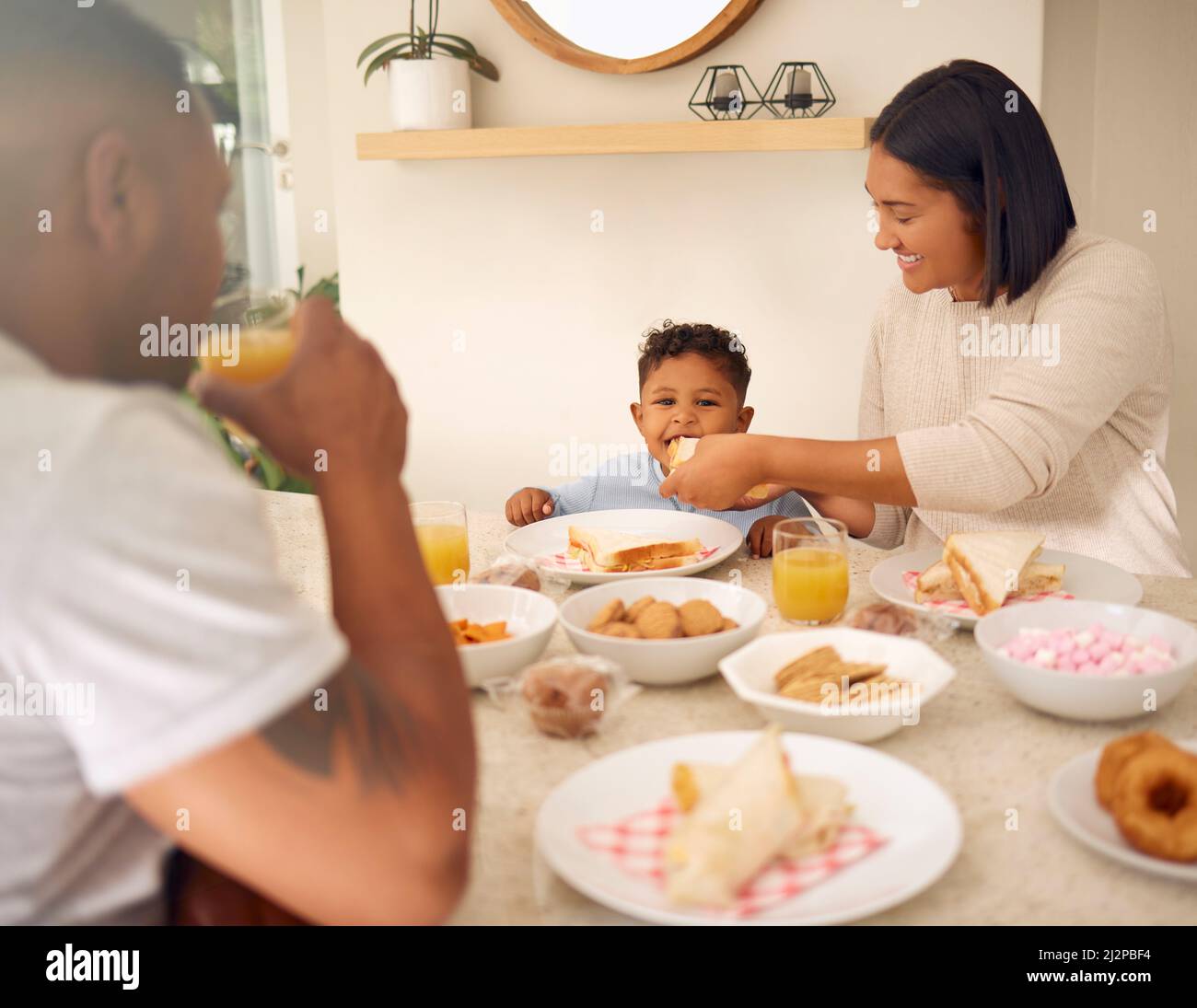 A little bite for my little boy. Shot of a happy young family having a leisurely lunch in their backyard at home. Stock Photo
